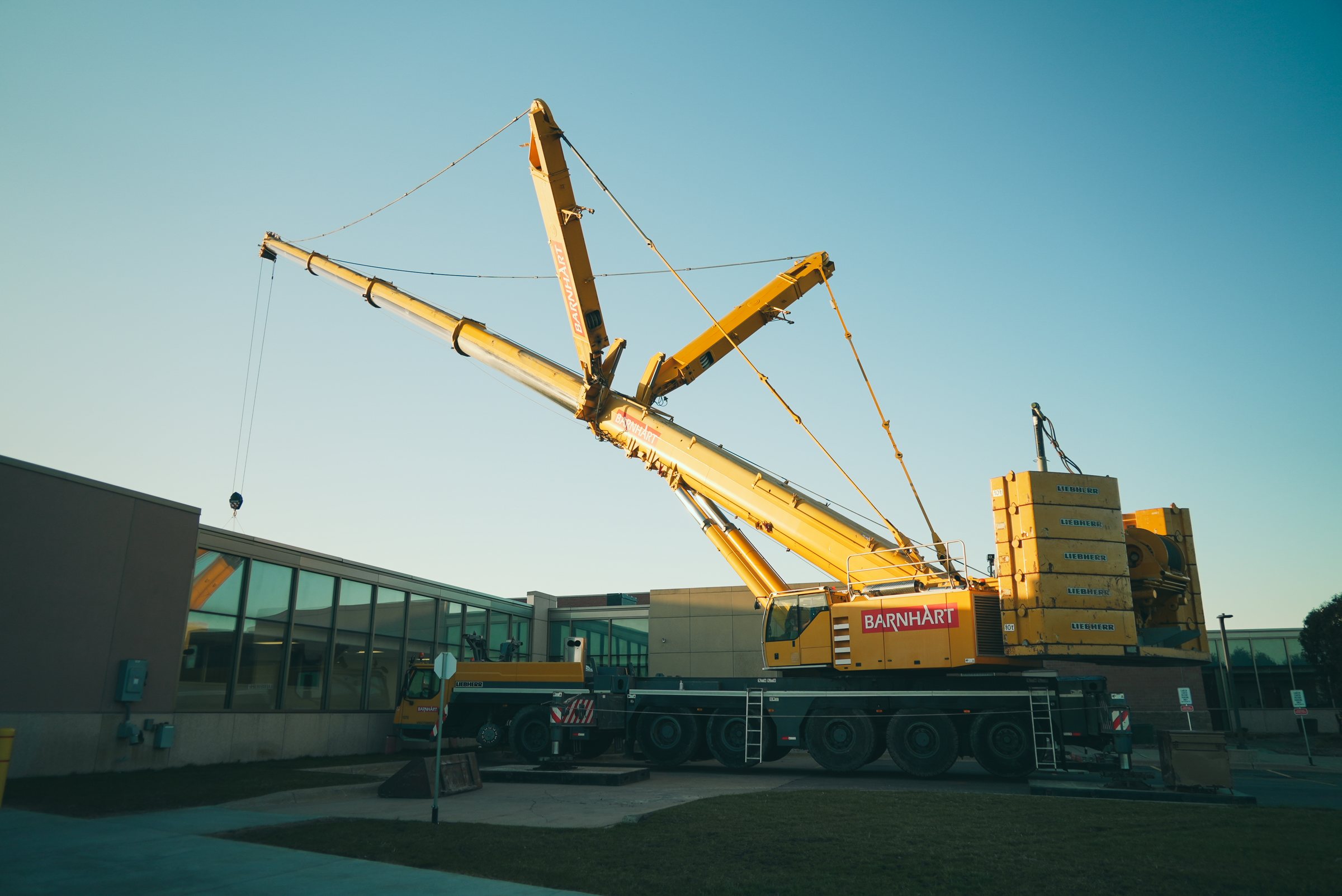 Yellow crane lifting beside a glass building